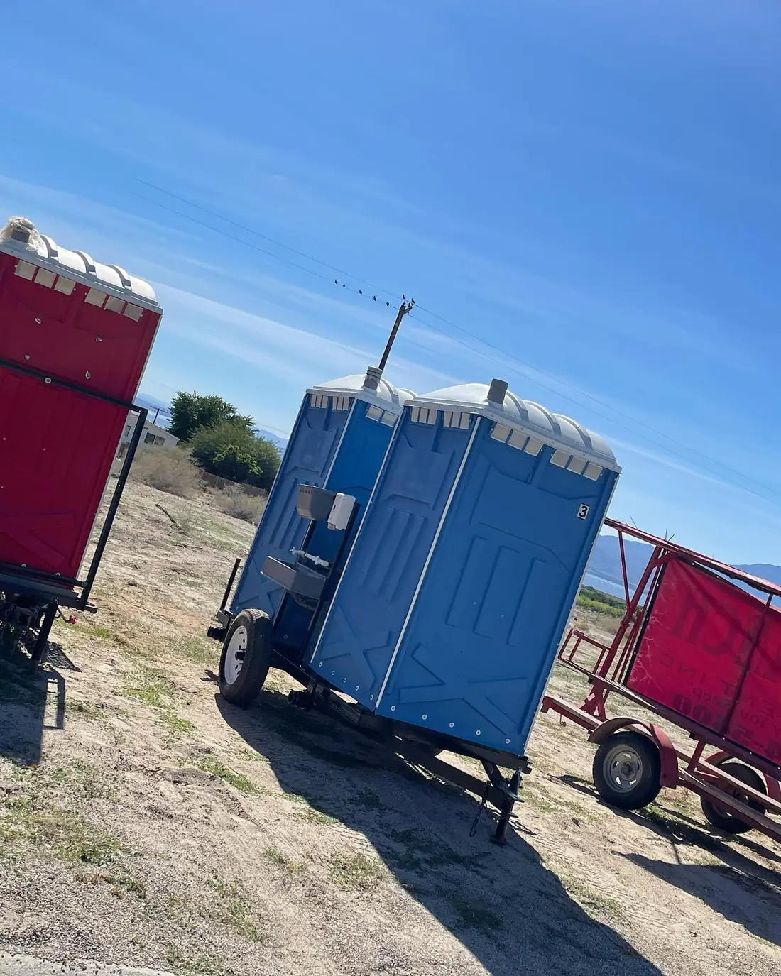 Towable portable toilet trailers parked on a dirt jobsite
