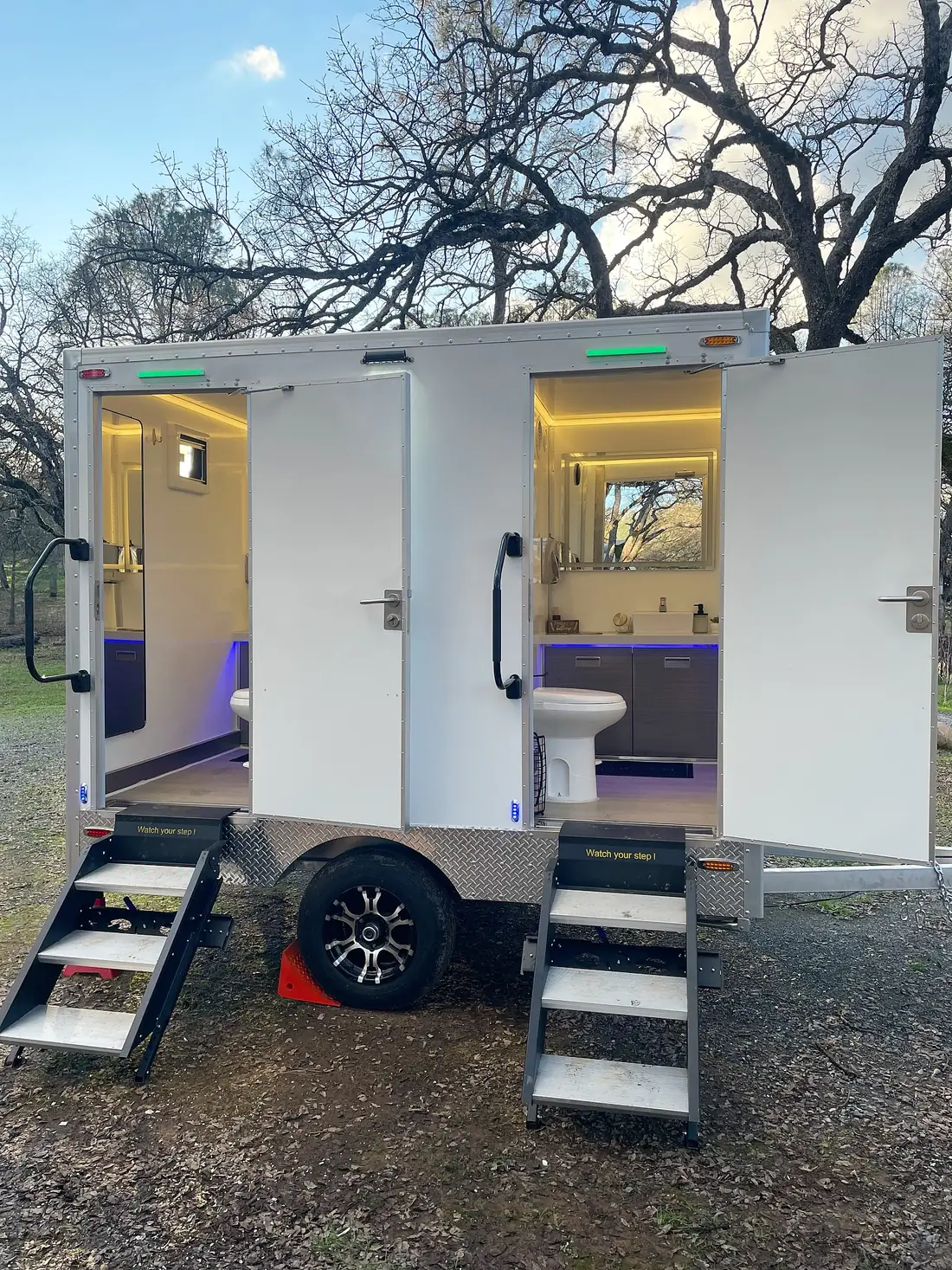 Two-room restroom trailer with lit interiors and fold-down steps